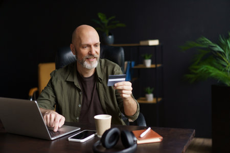 Online shopping, satisfied customer completes purchase. Customer use computer to browse goods. He enters data from credit card to make secure payment on online stores website. High quality photoの写真素材