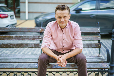 Charismatic and respectable man in portrait, sitting on city bench on street. Man exudes confidence and professionalism, showcasing sophisticated and charming demeanor. . High quality photoの写真素材