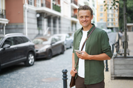 Lifestyle concept as handsome man is seen with mobile phone on charming streets of old city in Europe. urban backdrop evokes sense of history and culture, while mans presence adds modern touch to scene. . High quality photoの写真素材