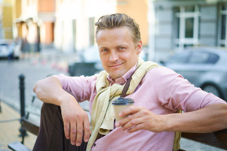 Street food concept of man enjoying tasty cup of coffee on bench outdoors. Aroma and flavor of coffee add to sensory experience of urban delight. Mans relaxed posture create sense of ease and leisure. . High quality photoの写真素材