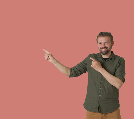 Man is depicted on a pink background, showcasing a dynamic and expressive gesture with his hands. He uses his hands to show arrows, indicating a sense of direction or movement. High quality photoの写真素材