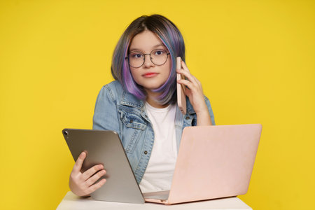Modern Technology In Daily Life, Teenage Girl Holding Laptop, Tablet Pc, And Mobile Phone. Isolated On Yellow Background, Concept Of Tech-Savvy Lifestyle, Devices Seamlessly Integrate Into Daily Activities. High quality photoの写真素材