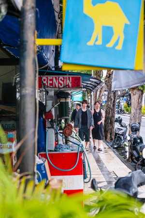 Pedestrians Passing a Roadside Fuel Kiosk on a Wet City Sidewalkのeditorial素材