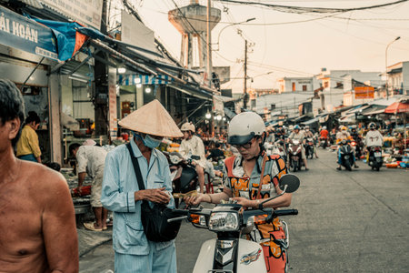 Duong Dong city on Phu Quoc Island. December 19, 2025. Bustling Street Scene in Vietnamese Town with Locals on Motorbikes and a Man in a Conical Hat at Sunset