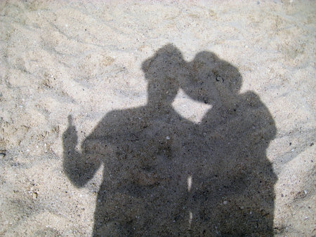 shadow  silhouette  a couple of tourists in hats on the sandの写真素材
