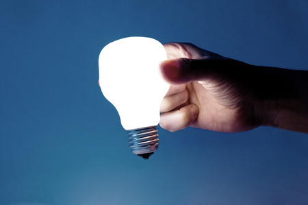 Glowing lamp in hand on blue background