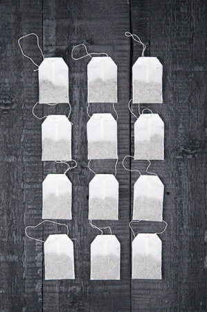 Teabags on black wooden backgroundの写真素材