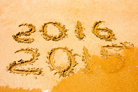New Year 2016 is coming concept - inscription 2015 and 2016 on a beach sand, the wave is starting to...