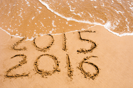 New Year 2016 is coming concept - inscription 2015 and 2016 on a beach sand, the wave is starting to...