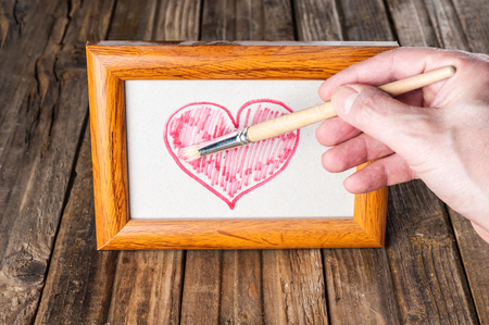 Hand drawing heart in old photo frameの写真素材