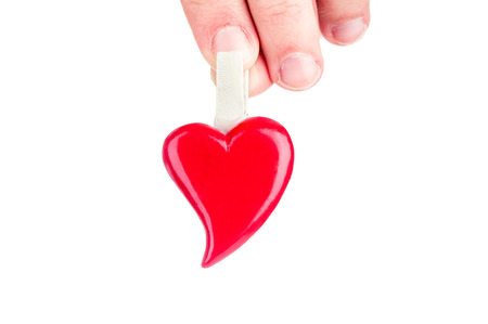 Hand holding red heart on white background