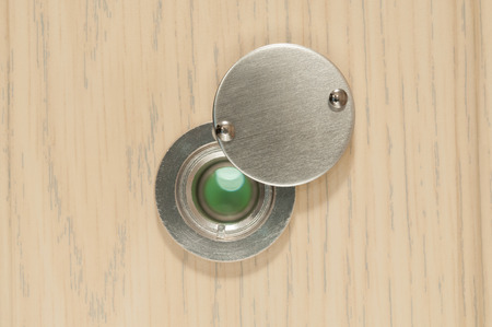 Peephole on wooden door close up