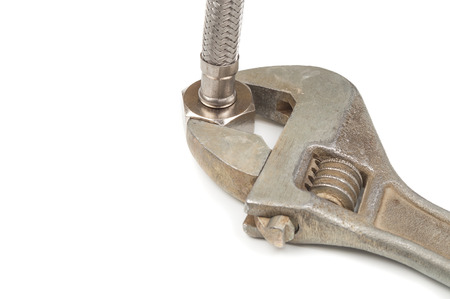 Wrench screwing nut of water pipe close up on white backgroundの写真素材