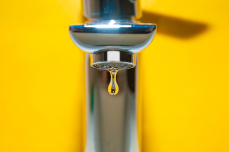 Tap with water drop on yellow backgroundの写真素材
