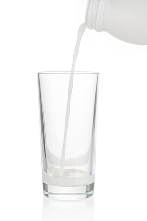 Pouring milk in glass on white backgroundの写真素材