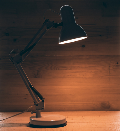 Glowing table lamp on wooden desk close upの写真素材