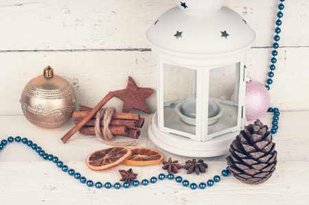 Christmas card with candlelight, cinnamon and pine cone on wooden background. Toned imageの写真素材