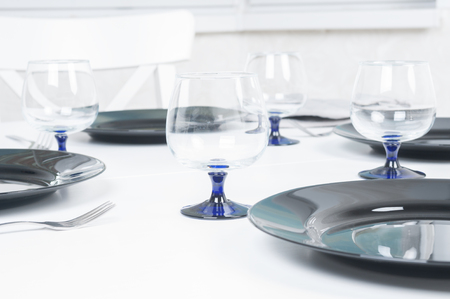 Empty plates and wineglasses on white tableの写真素材