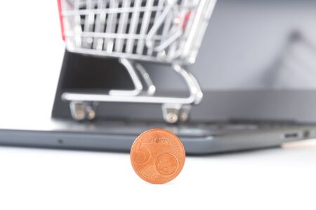 Five euro cent close up and laptop with trolley cart on white backgroundの写真素材