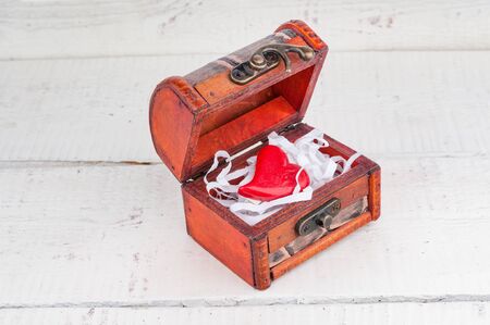 Heart in vintage chest on wooden background. Valentines day card