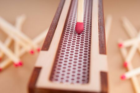 Match rubbing from side of matchbox and few matchsticks on brown background