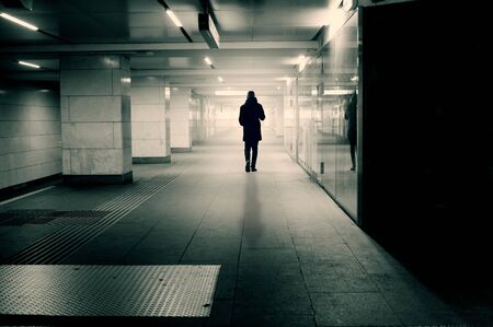 Silhouette of alone man in tunnel walking towards a bright lightの写真素材