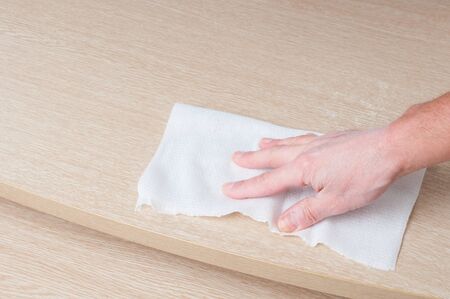 Hand cleaning of wooden table with paper towel