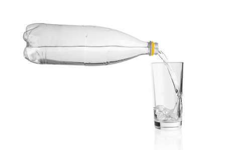 Flowing soda water from plastic bottle into glass on white background