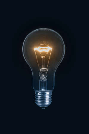 Glowing light bulb close up on black background