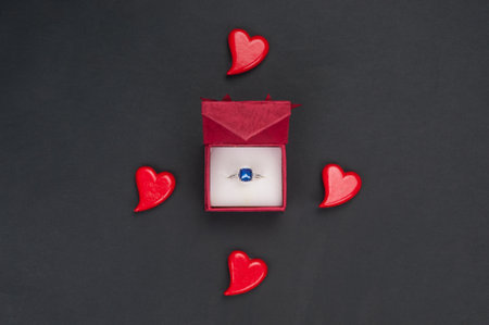Red hearts and case with ring with blue gem on black background. Valentines day cardの写真素材