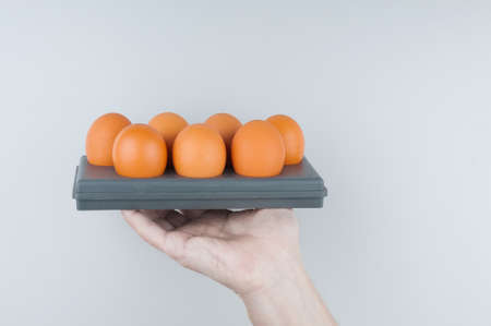 Hand holding container with eggs on gray backgroundの写真素材