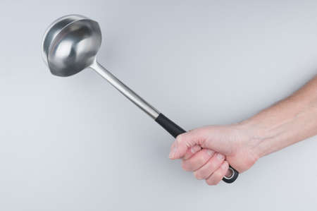Hand holding kitchen spoon on gray backgroundの写真素材