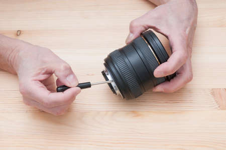 Manual repair process of camera lens on wooden backgroundの写真素材