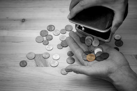 Hands with old purse and some euro cents on wooden background