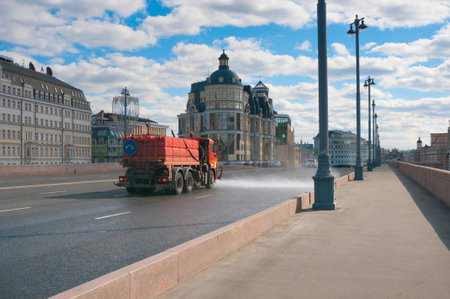 Moscow, Russia - april 05, 2021: Ð¡ity watering machine is watering the roadway in downtownのeditorial素材