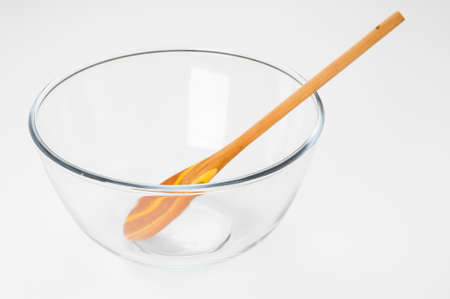 Empty glass food bowl with wooden spoon on white backgroundの写真素材