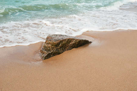 Single stone in sand on a sea coastの写真素材
