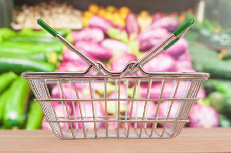 Empty shop basket on blurring supermarket vegetable shelf backgroundの写真素材