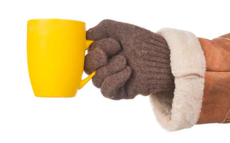 Man hand in warm glove holding yellow cup on white backgroundの写真素材