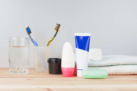 Toothbrushes with water glass, paste, soap and towel on wooden backgroundの写真素材