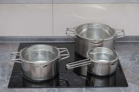 Stainless saucepans on electric stove in a kitchenの写真素材