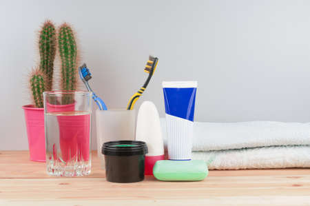 Toothbrushes with cactus, water glass, paste, soap and towel on wooden backgroundの写真素材