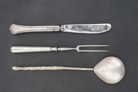 Antique metal knife, fork and spoon on black backgroundの写真素材