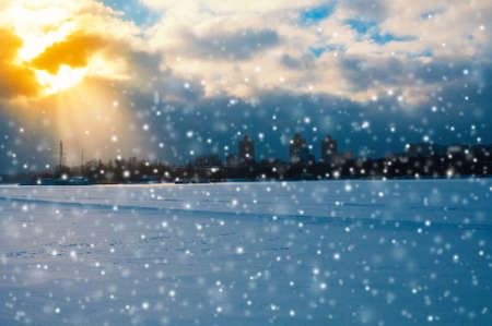 Snowfall at frozen river in a winter city landscapeの写真素材