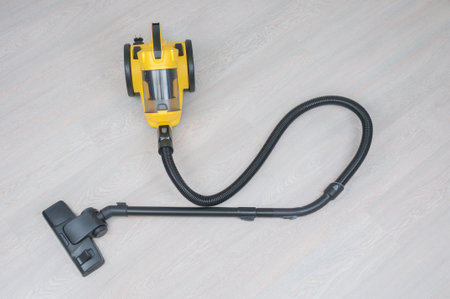 Yellow vacuum cleaner with hose and brush on wooden floorの写真素材
