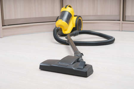 Yellow vacuum cleaner with sweeping brush on a wooden floor. front focusの写真素材