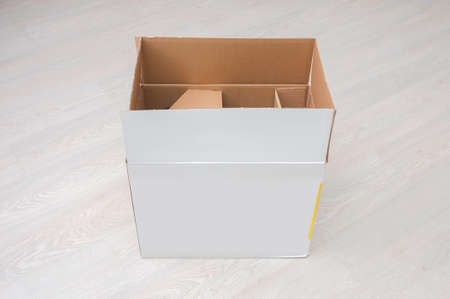 Open cardboard box close up on a wooden floor