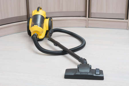 Yellow vacuum cleaner with sweeping brush on a wooden floorの写真素材