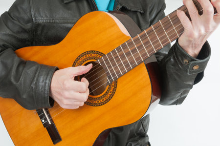Man in leather jacket playing on acoustic guitar close upの写真素材
