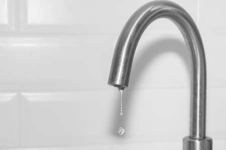 Metal tap and falling water drop close up